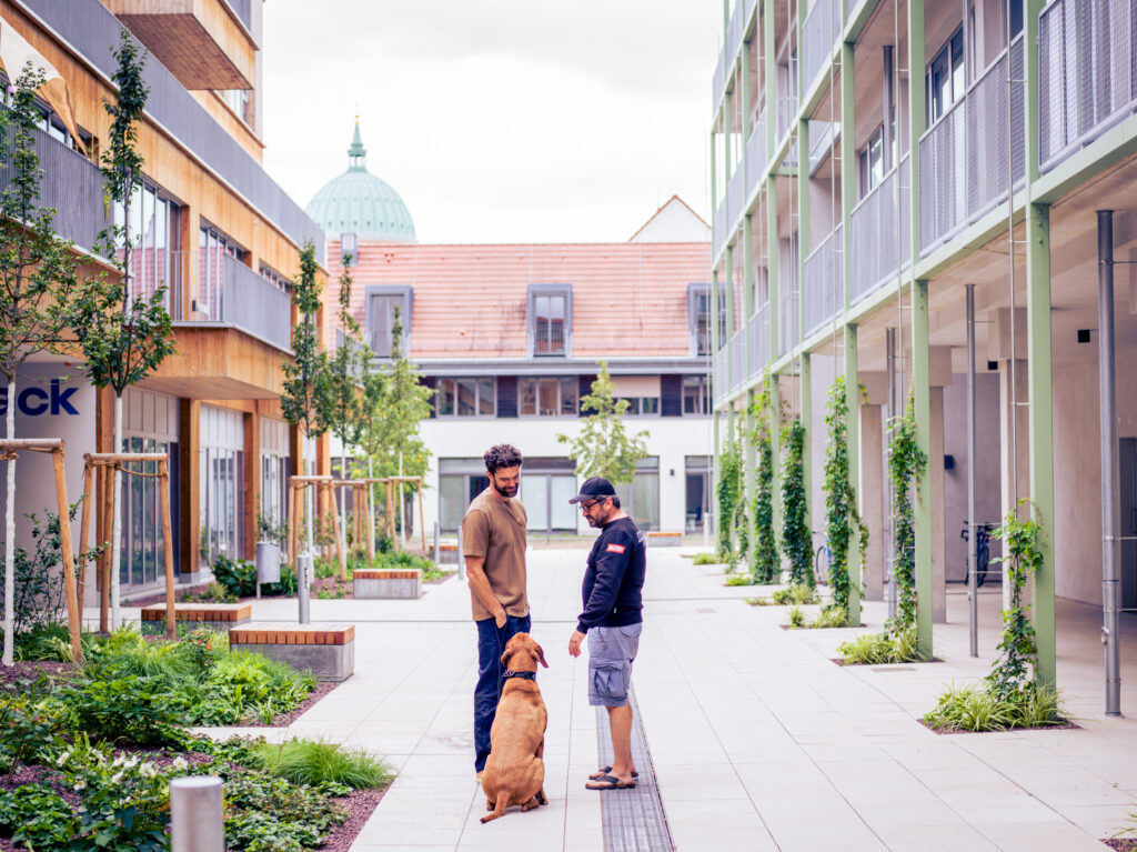 Zwei Männer mit Hund im Gespräch in der Gasse des Kreativ Quartiers, im Hintergrund die Nikolaikirche